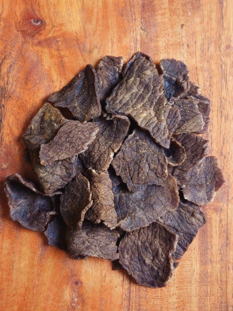 Bitcoin Beef Bits, dried beef pieces displayed on a wooden board.