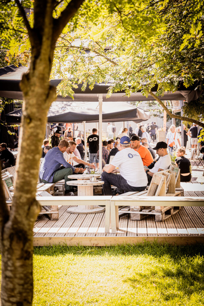 Bitcoin community gathering outdoors — people networking under shade at BTCHEL